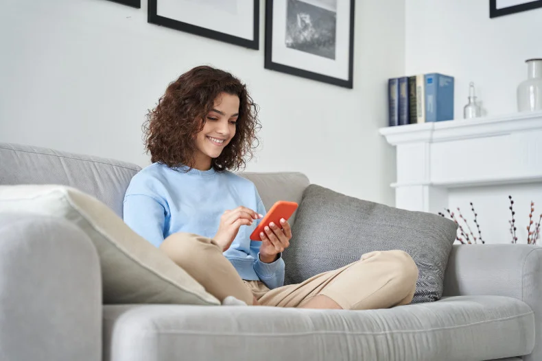 Smiling young latin woman blogger subscribing new social media, buying in internet, ordering products online at Jtaime Skin Co.